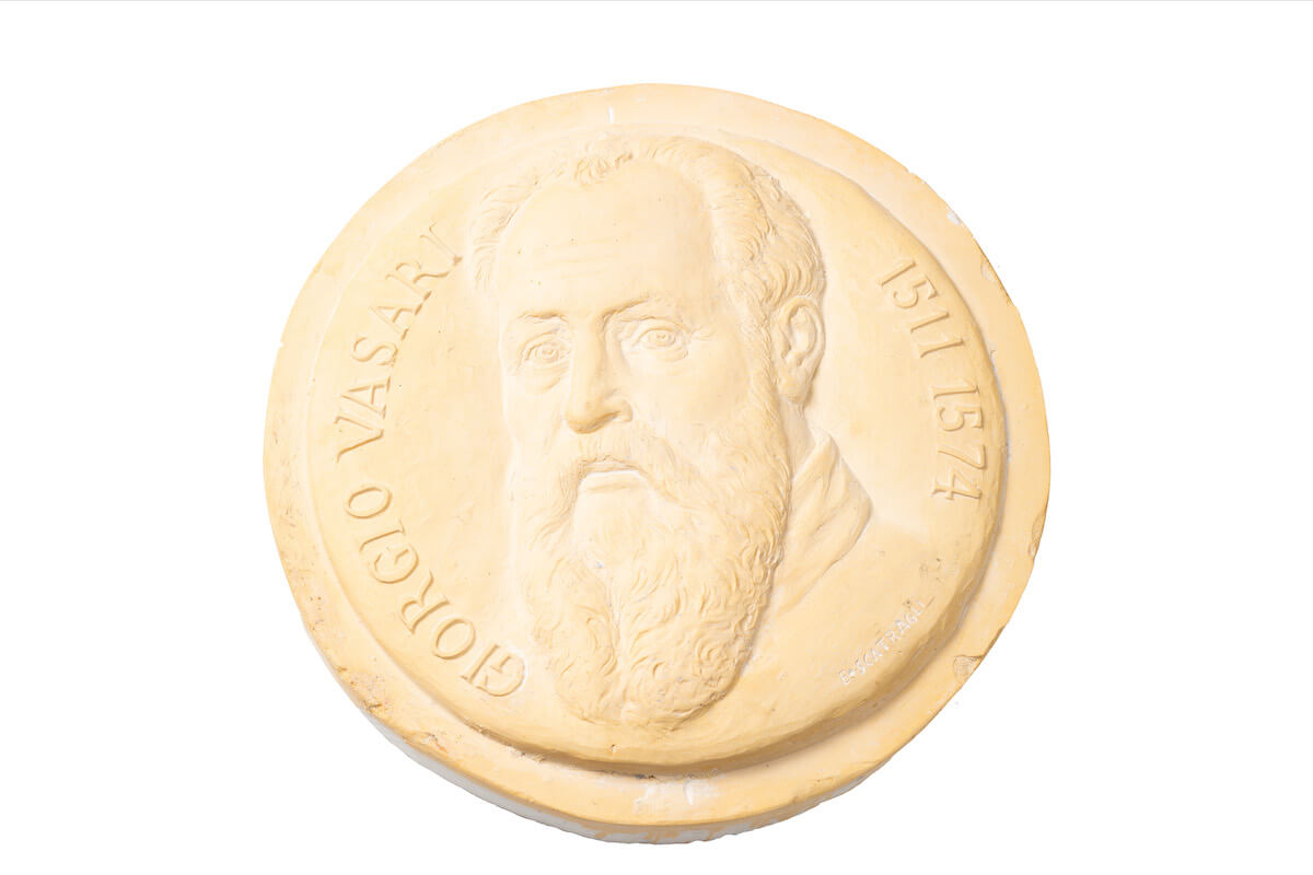 Medaglione chiaro con busto in rilievo di Giorgio Vasari e iscrizione perimetrale “GIORGIO VASARI 1511 1574”.